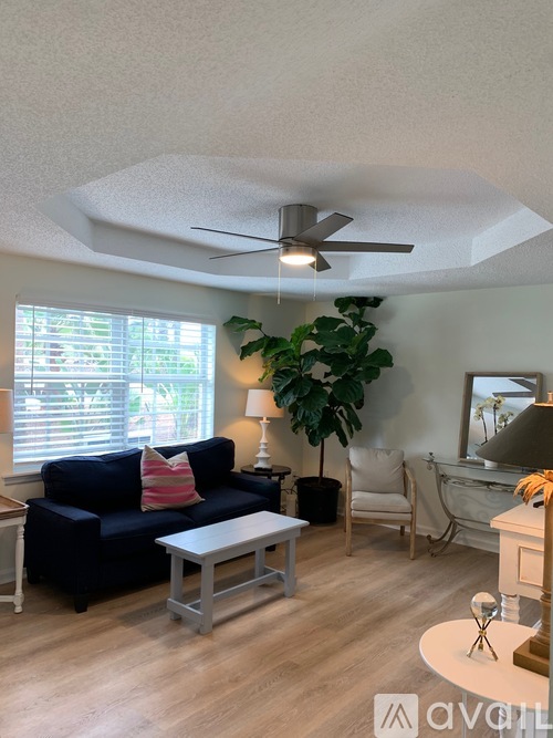 A living room with a blue couch, a white coffee table, and a ceiling fan.