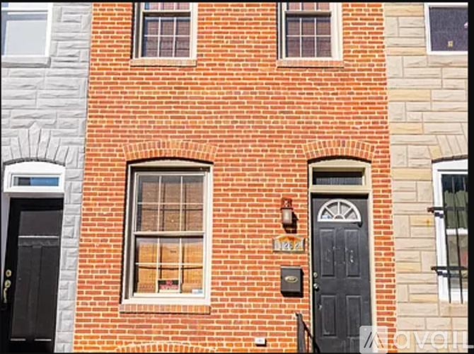 A red brick building with a black door and a window with a white frame.