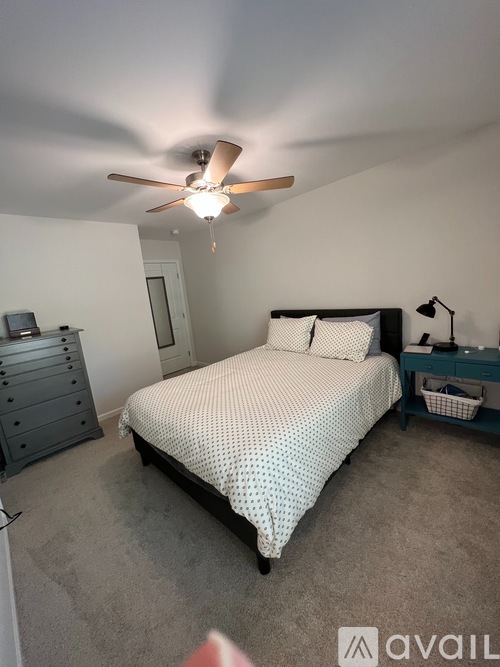 A bedroom with a bed, dresser, and ceiling fan.