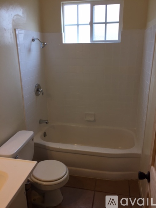 A white toilet and bathtub in a bathroom with a window.