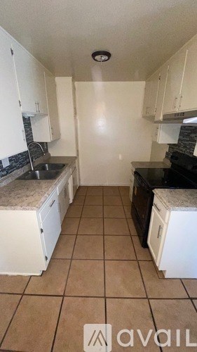 A kitchen with white cabinets and a tiled floor.