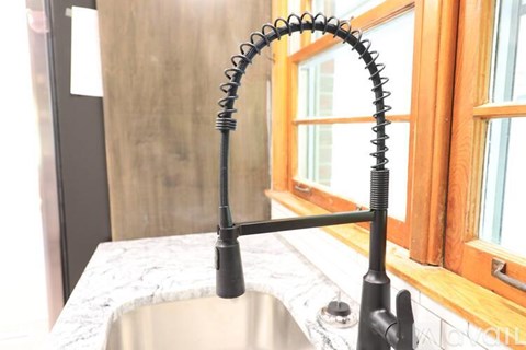 A kitchen sink with a black faucet and a metal spout.