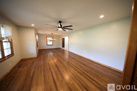 A spacious room with wooden floors and a ceiling fan.