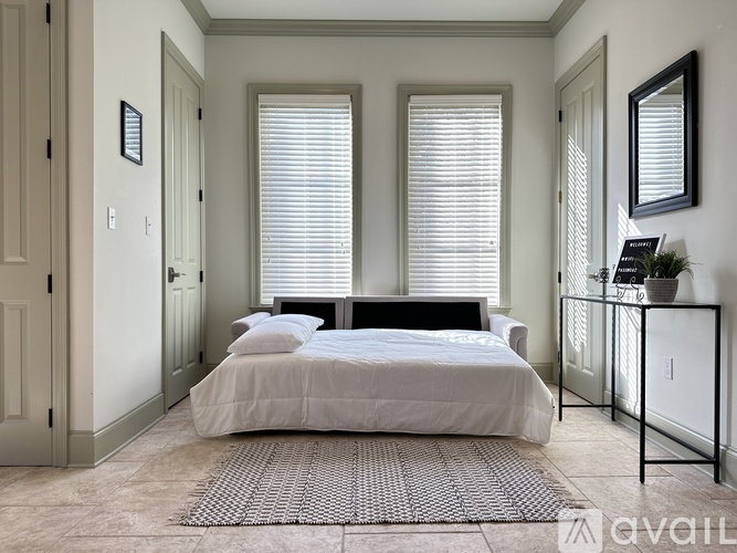 A bedroom with a large bed and a window with blinds.
