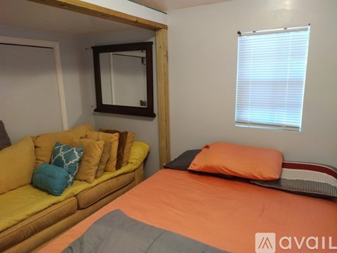 A bedroom with a bed, couch, and window.
