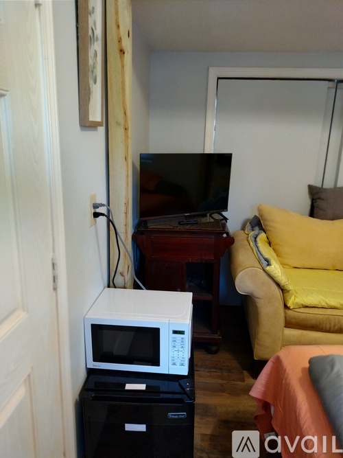 A white microwave oven is on top of a black computer tower.