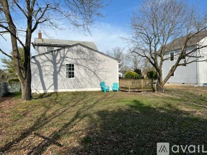 A white barn-like building with a tree in front of it.