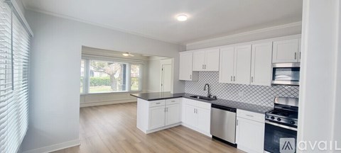 A kitchen with white cabinets and a black countertop.