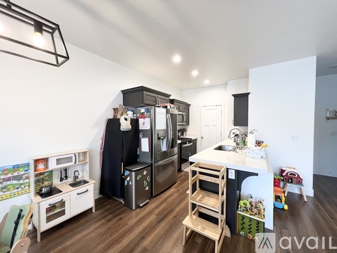 A kitchen with a black refrigerator, white cabinets, and a wooden table.