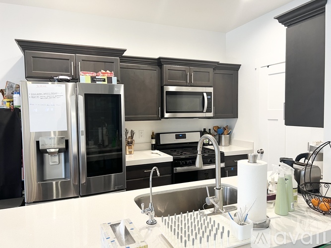 A kitchen with a sink, refrigerator, and microwave.