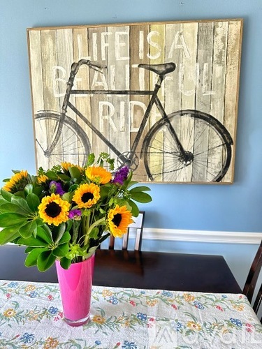 A wooden sign with a bicycle and the words "Life is a bicycle ride" is on the wall.