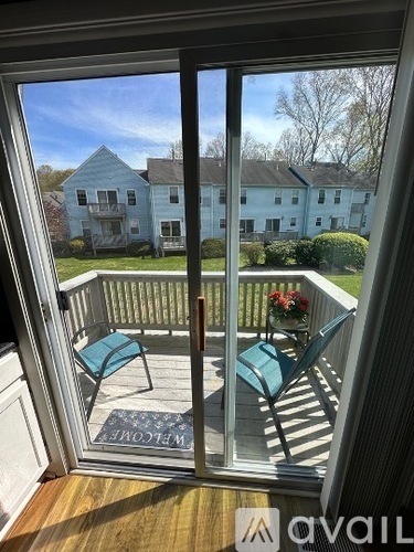 A balcony with a table and chairs overlooking a blue house.