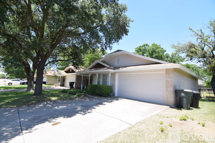 A house with a white garage door and a tree in front.