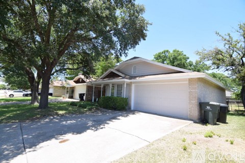 A house with a white garage door and a tree in front.