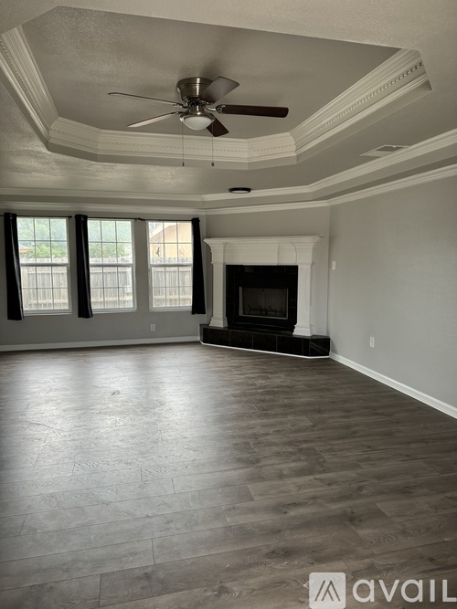 A spacious living room with a fireplace and a ceiling fan.