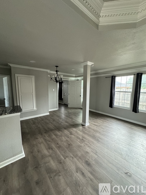 A spacious room with wooden floors and a chandelier hanging from the ceiling.