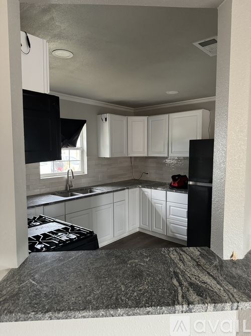 A kitchen with black and white cabinets and a black stove top.