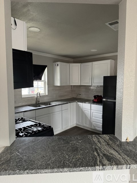 A kitchen with black and white cabinets and a black stove top.