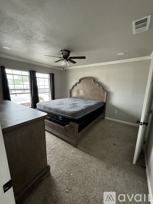 A bedroom with a bed, dresser, and window.