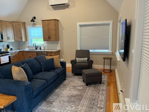 A living room with a blue couch and a television on the wall.