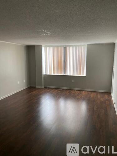A room with wooden flooring and a window with blinds.
