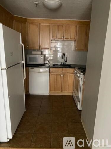 A kitchen with white appliances and brown cabinets.