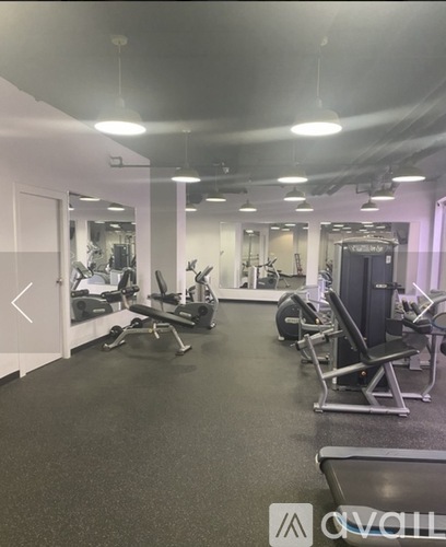 A gym with various exercise equipment and a mirror on the wall.