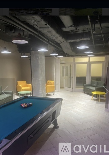 A pool table is in the middle of a room with a yellow chair and a green chair.