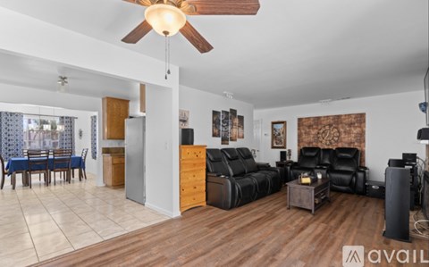A living room with a black leather couch and a wooden floor.