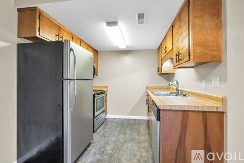 A kitchen with wooden cabinets and a black refrigerator.