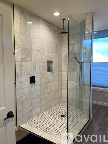 A bathroom with a walk-in shower and a glass door.