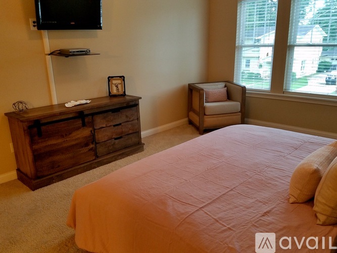 A bedroom with a bed, a chair, and a wooden dresser.
