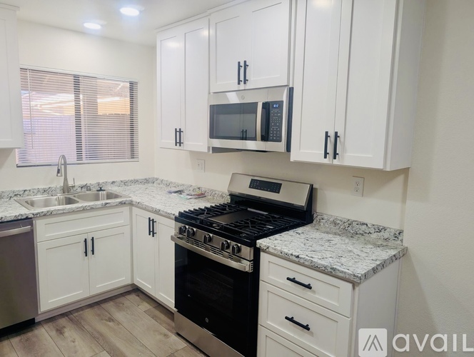 A kitchen with white cabinets and a granite countertop.