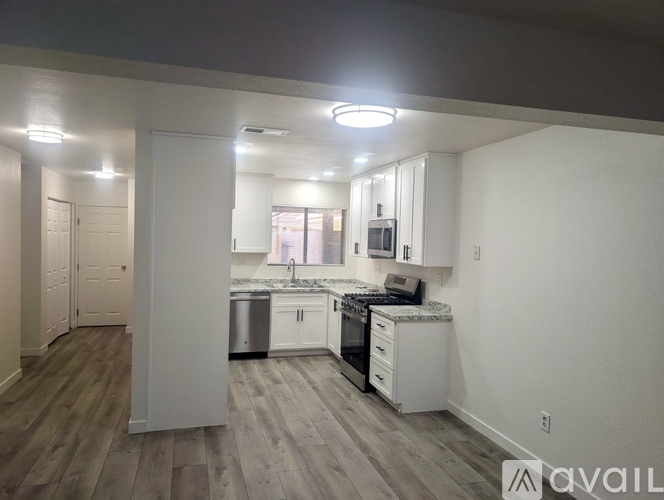 A kitchen with white cabinets and a wooden floor.