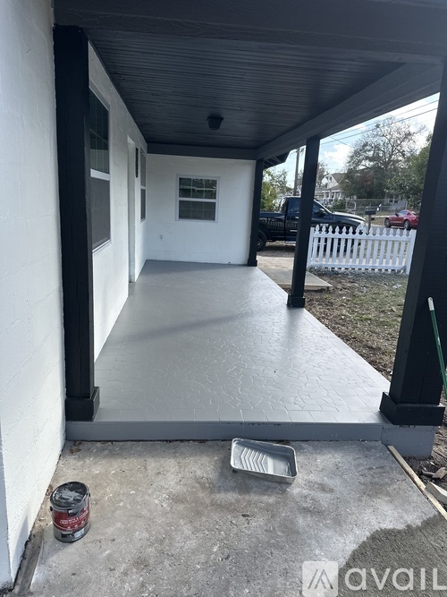 A white porch with a black railing and a can of paint on the ground.