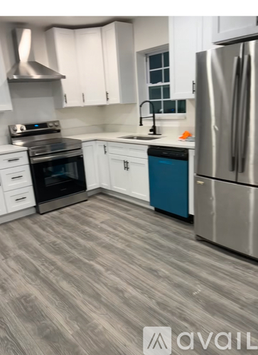 A kitchen with a stainless steel refrigerator, a stove, and a blue trash can.