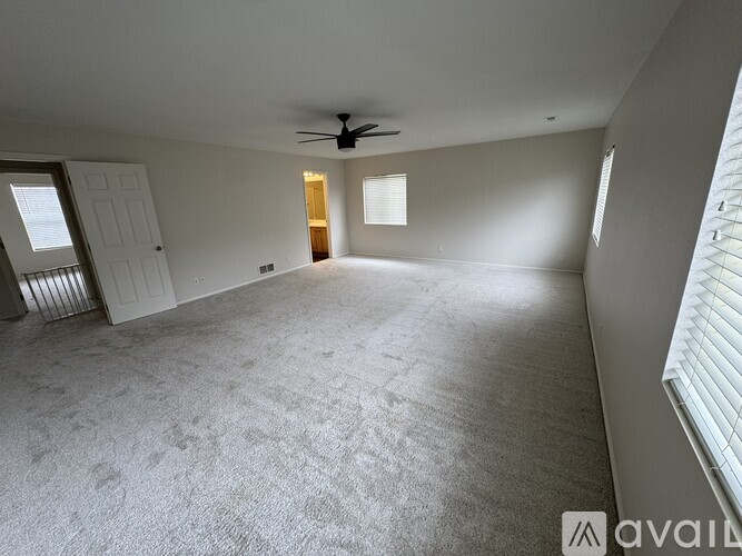 A spacious room with a carpeted floor and a ceiling fan.