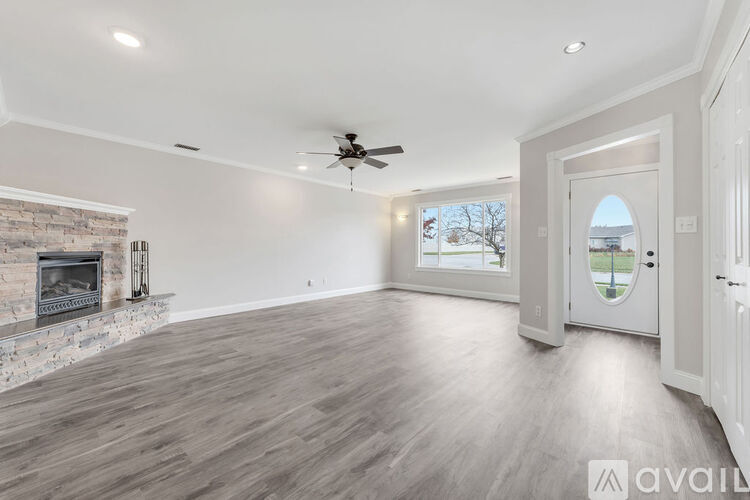 A spacious room with a fireplace and a ceiling fan.