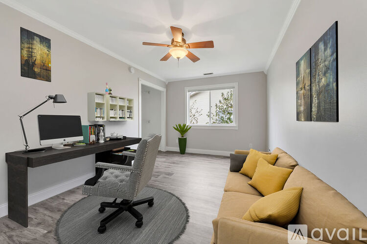 A living room with a brown couch and a desk with a computer.