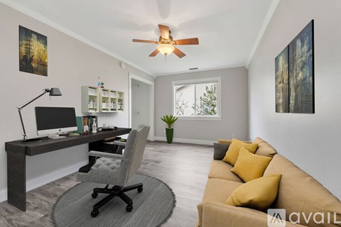 A living room with a brown couch and a desk with a computer.