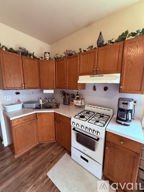 A kitchen with wooden cabinets and a white stove top oven.
