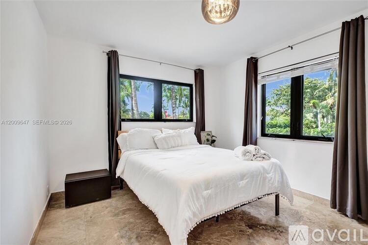 A bedroom with a large bed and a window overlooking a tree.