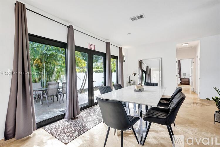 A dining room with a table and chairs and a view of the outdoors.