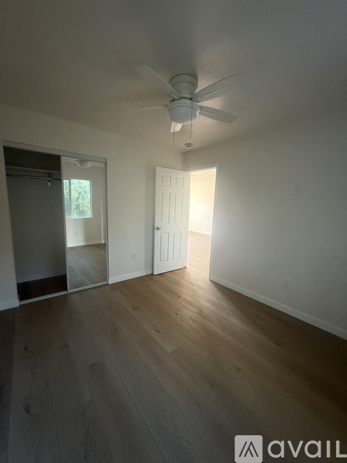 A room with a ceiling fan and wooden flooring.