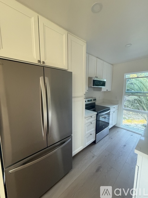 A kitchen with a stainless steel refrigerator and white cabinets.