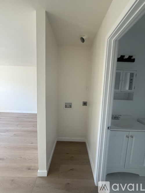 A white hallway with a doorway leading to a bathroom.