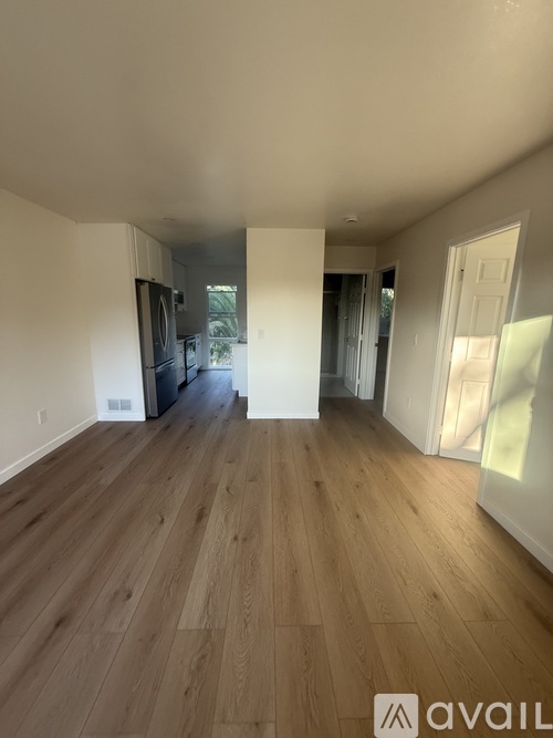 A spacious room with wooden flooring and white walls.