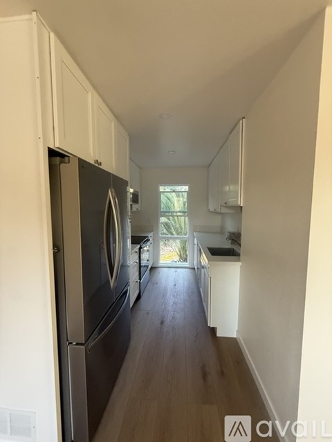A kitchen with white cabinets and a black fridge.