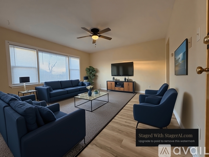 A living room with a dark blue sofa, a glass coffee table, and a flat-screen TV mounted on the wall.