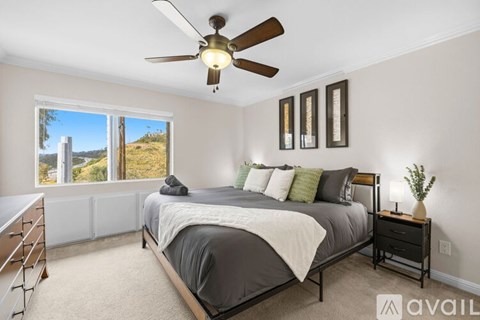 A bedroom with a large bed and a ceiling fan.